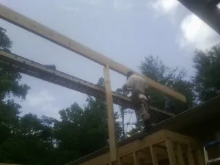 Carpenter setting a ridge beam over a new addition frame — Ice Dam Removal by Roofing Brothers in Sanderson