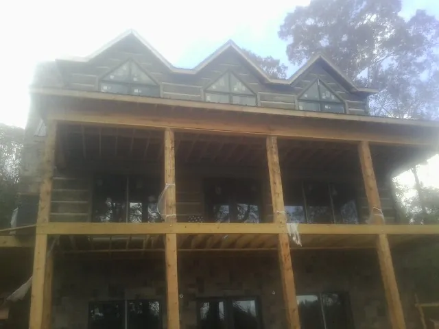 Dormers and porch framing on a large log home under construction — Roof Coating work by our crew in Sanderson