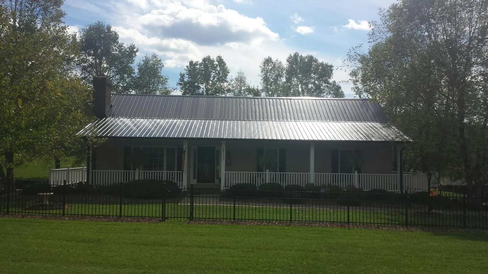 Gray metal roof on a brick ranch with a full width front porch — Gutter Guard Installation work by our crew in Sanderson