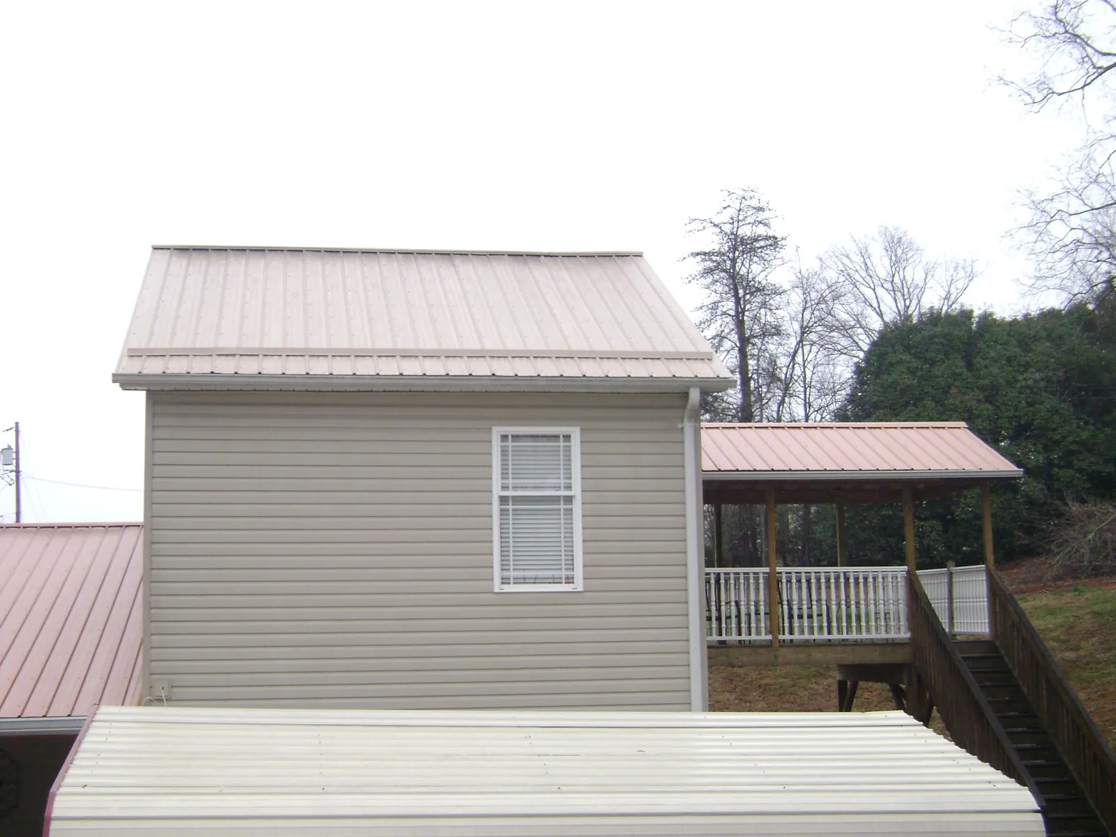Tan metal roofs on a two story addition and attached porch, from a Roof Replacement job in Sanderson