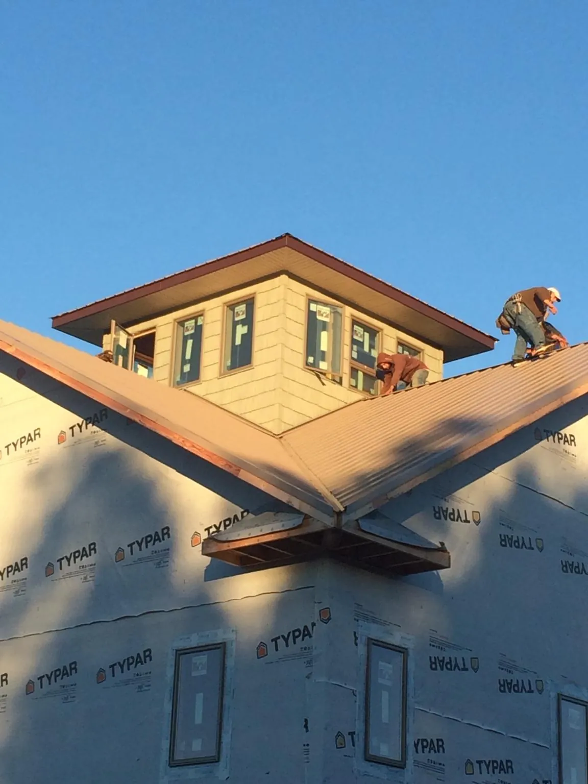 Roofers working around a rooftop cupola on a new metal roof at sunset — Roof Waterproofing in Sanderson by Roofing Brothers
